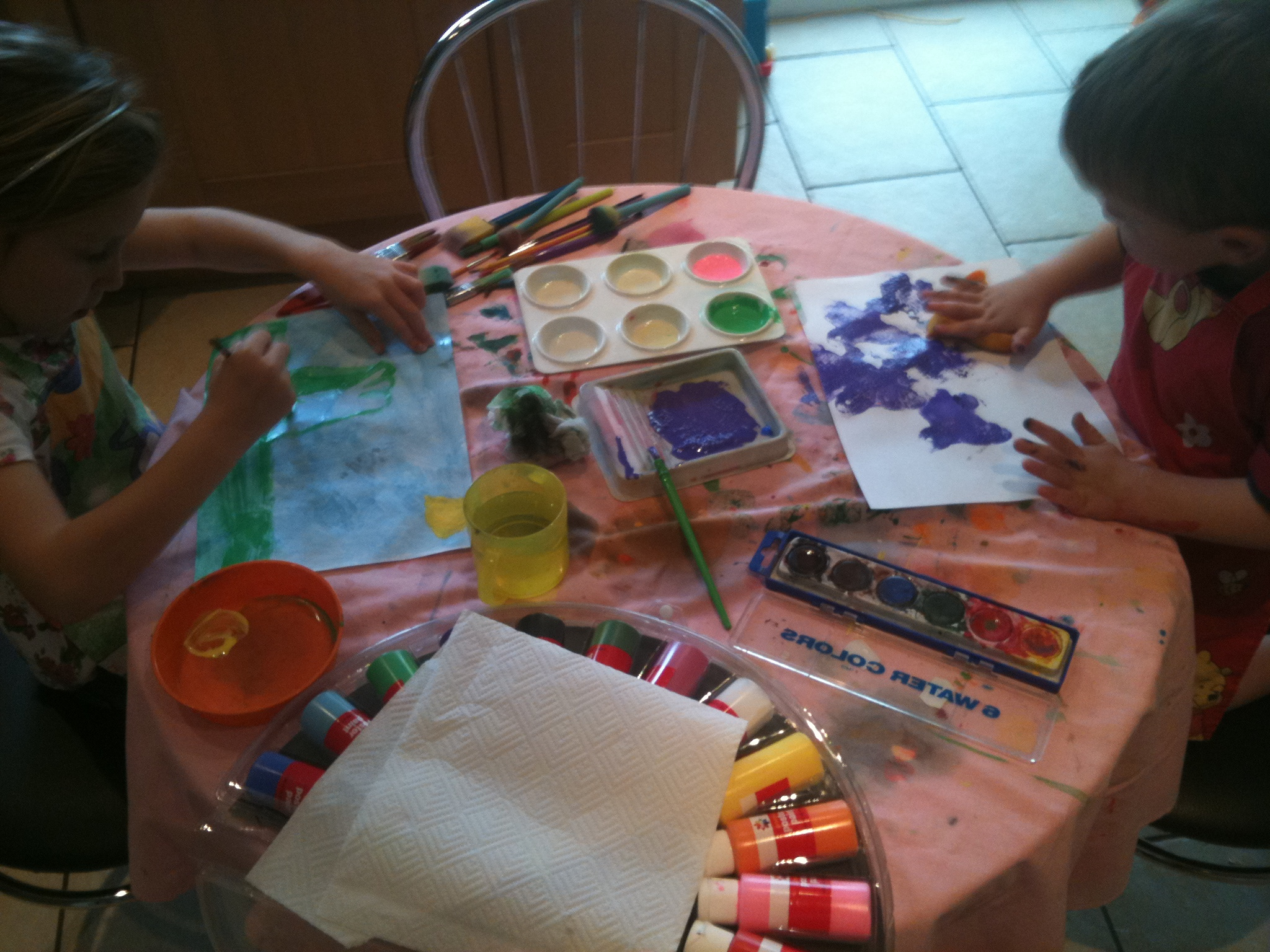 two children are painting with paints on paper