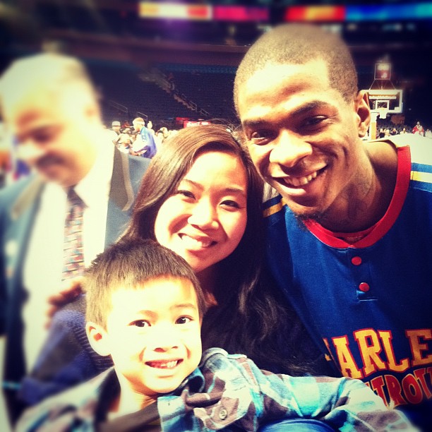 a woman and boy smile at the camera with a basketball player