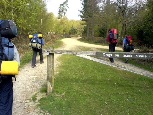 the people are walking along the path with the sign in front of them