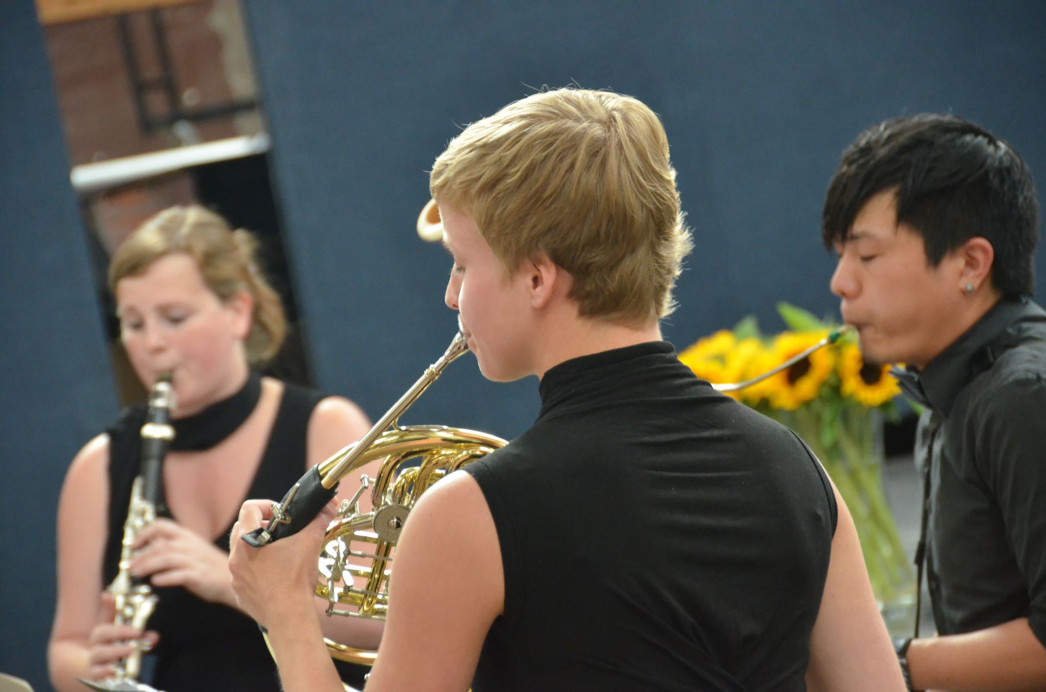 three people standing near one another playing instruments