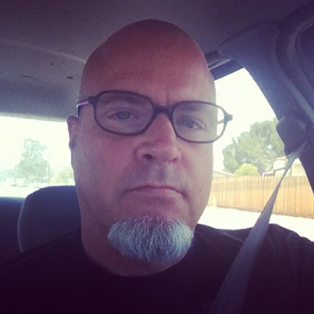 a man with glasses and grey beard and glasses sitting in the back seat