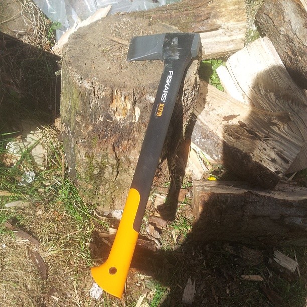 an axe with an orange handle sitting on a tree
