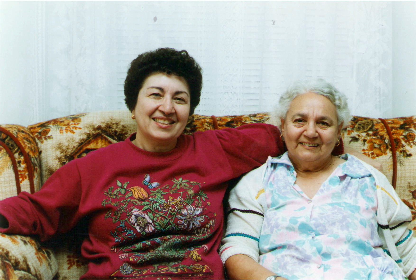 two older women sit on a couch together