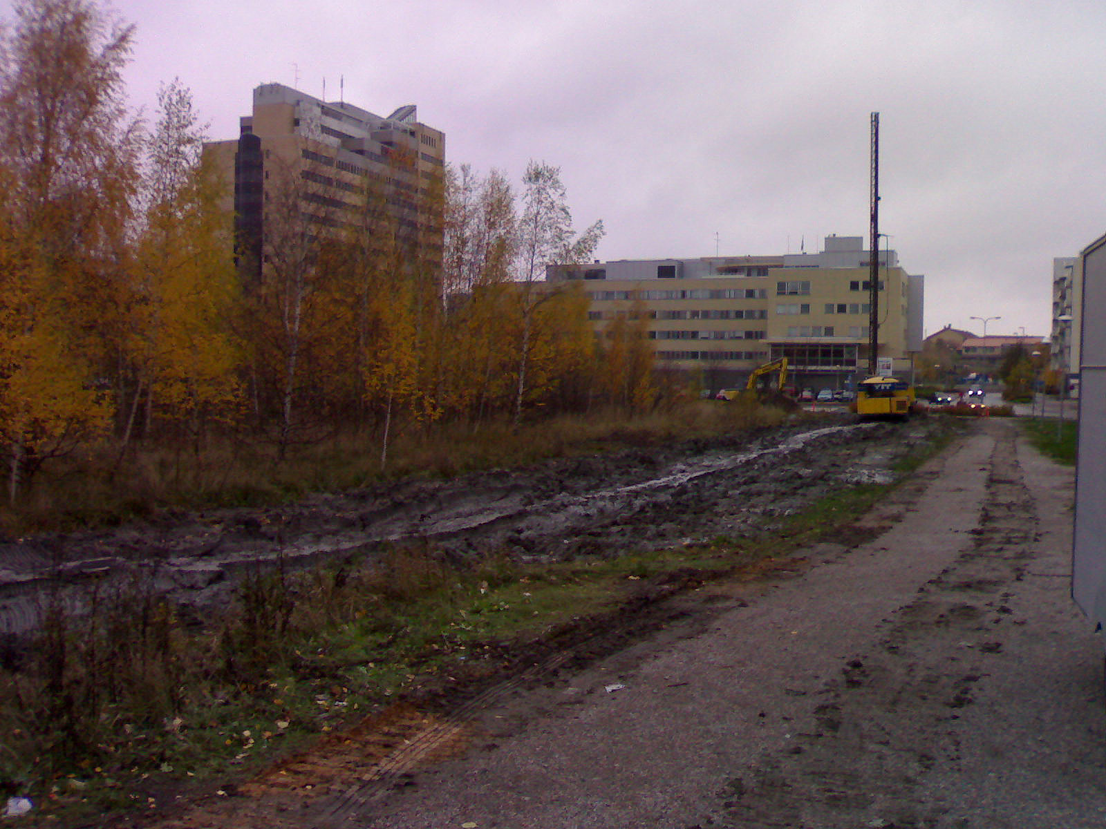 a gravel road near the road and some buildings