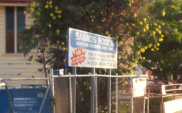 a sign stands behind a fence that is in front of a house