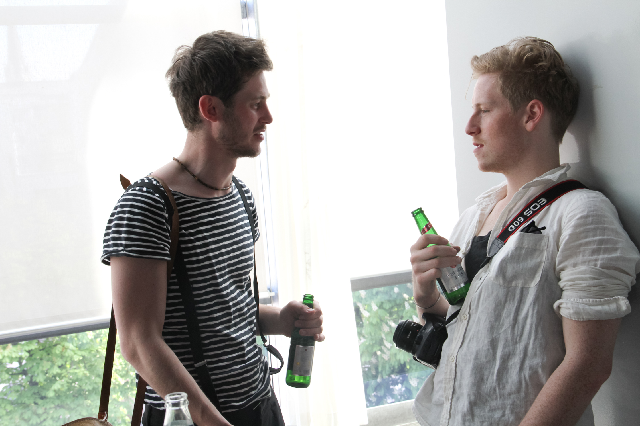 a young man standing next to a person holding two beers