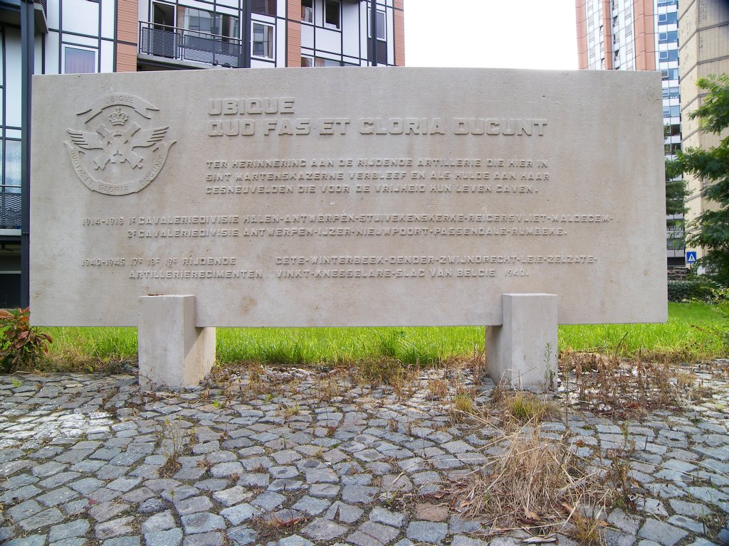 a sign sitting in front of a building with lots of stone benches