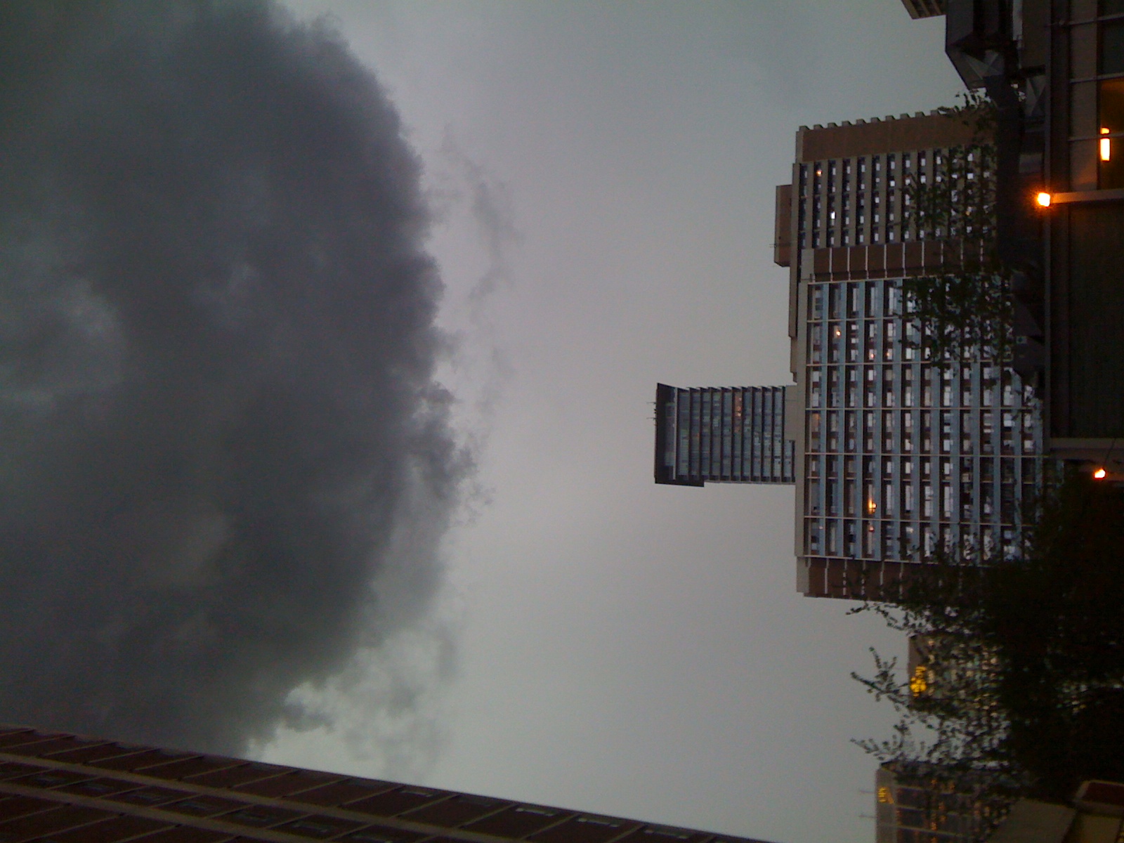 a storm in the distance with dark clouds over buildings