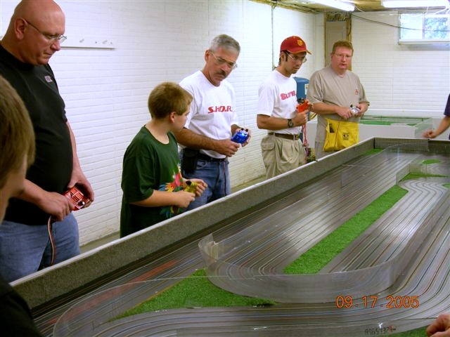 a group of men watch as a boy plays a track