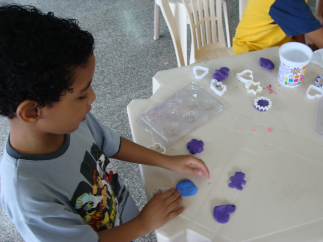 a young child playing with dough while wearing glasses