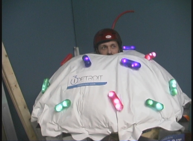 the man has been dressed as a bug and is wearing a light up jacket