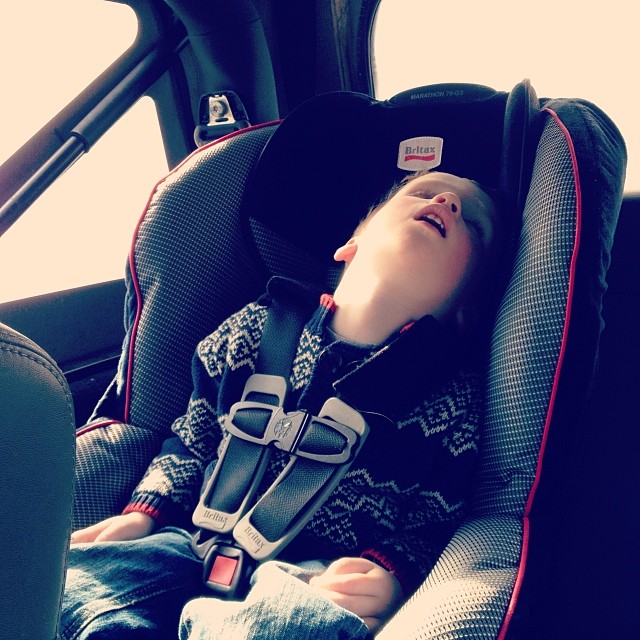 a child sleeping in a car seat with another child