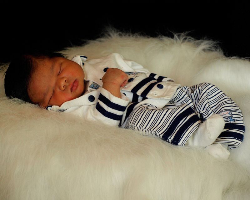 a baby boy sleeping on white fur covered in his outfit
