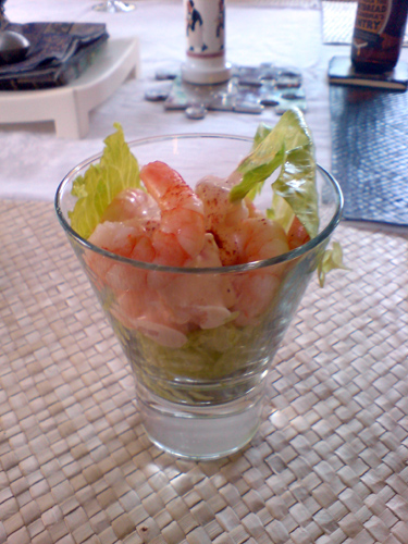 a glass bowl containing shrimp and lettuce on a table