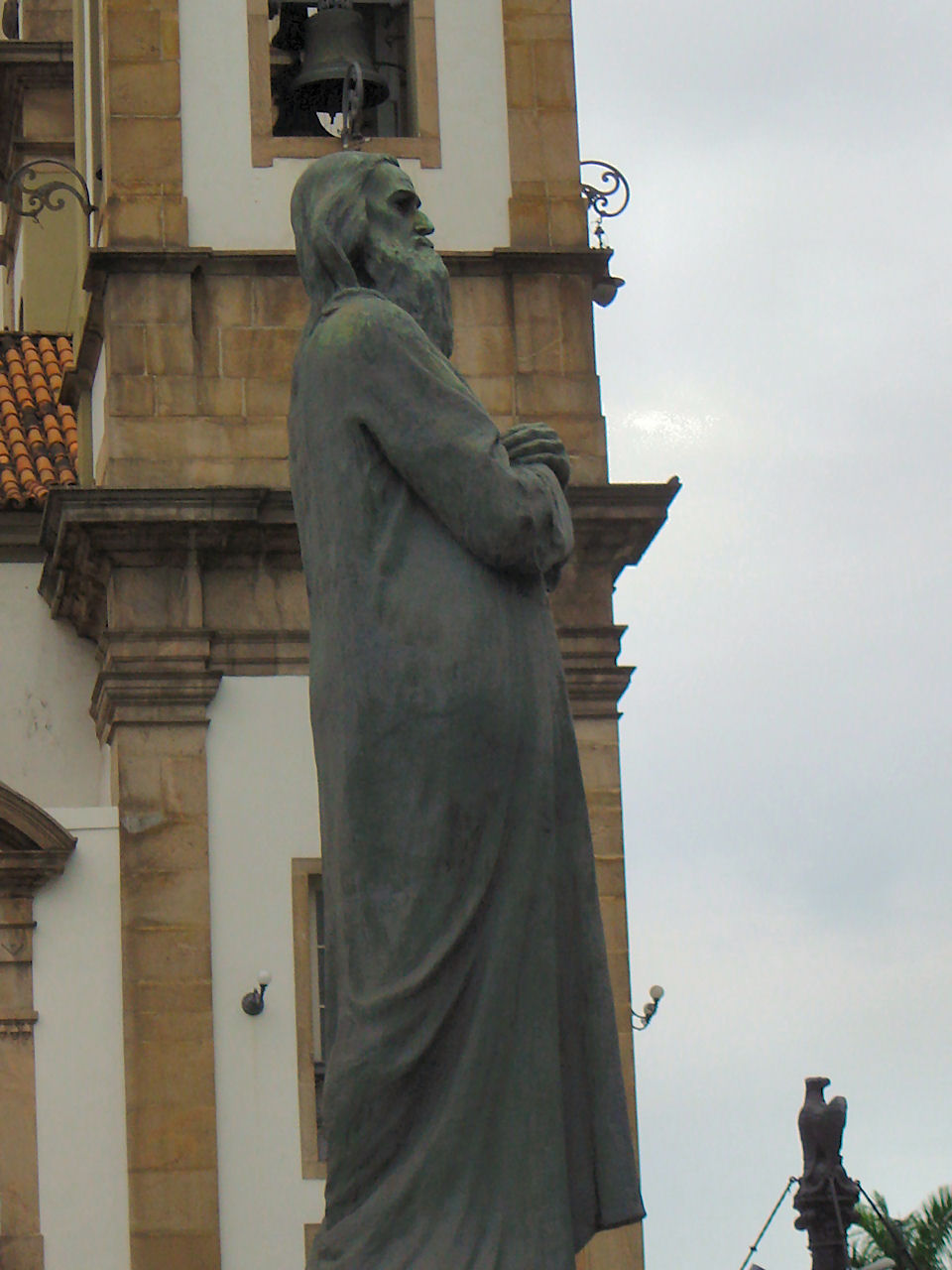 the statue is holding the bell tower in the daytime