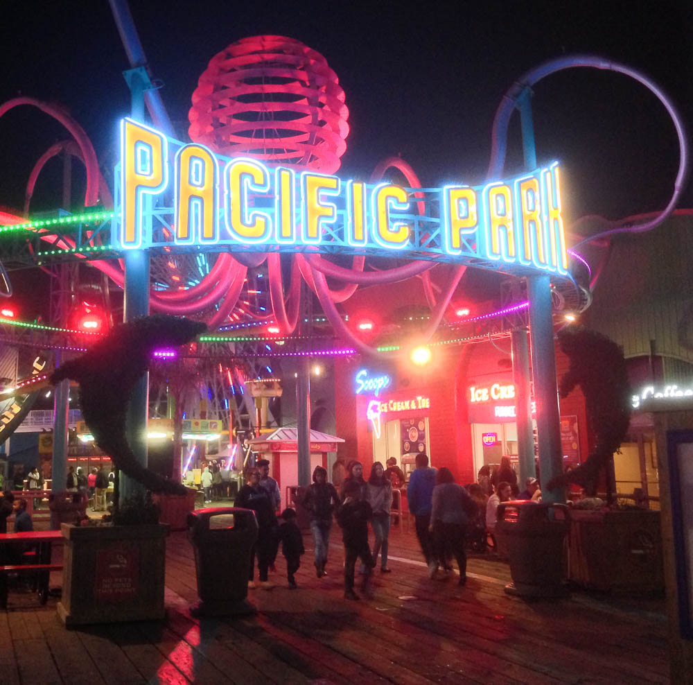 a crowd of people walk under a colorful light display at an amut park