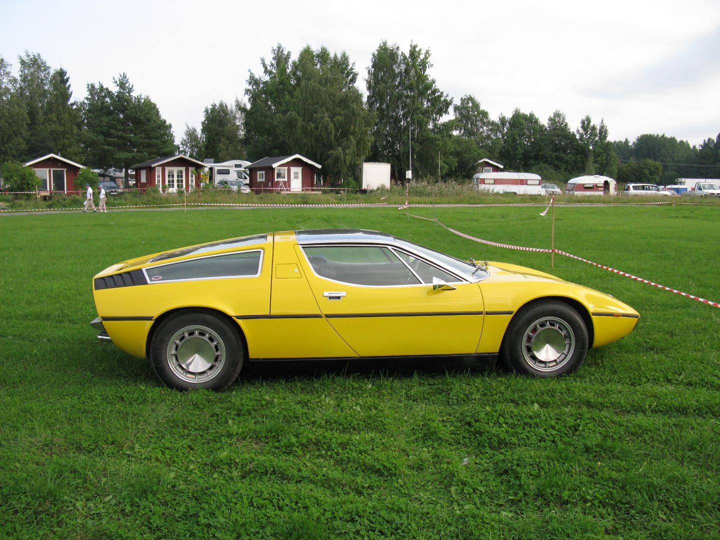 a yellow car that is parked in some grass