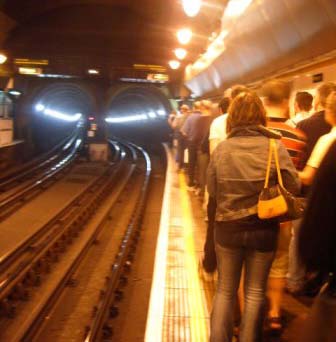 people standing on a subway platform waiting for a train