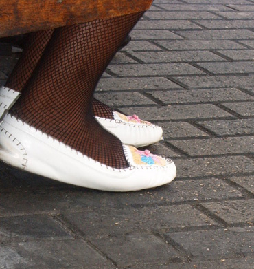 woman in fishnet tights and shoes under the table