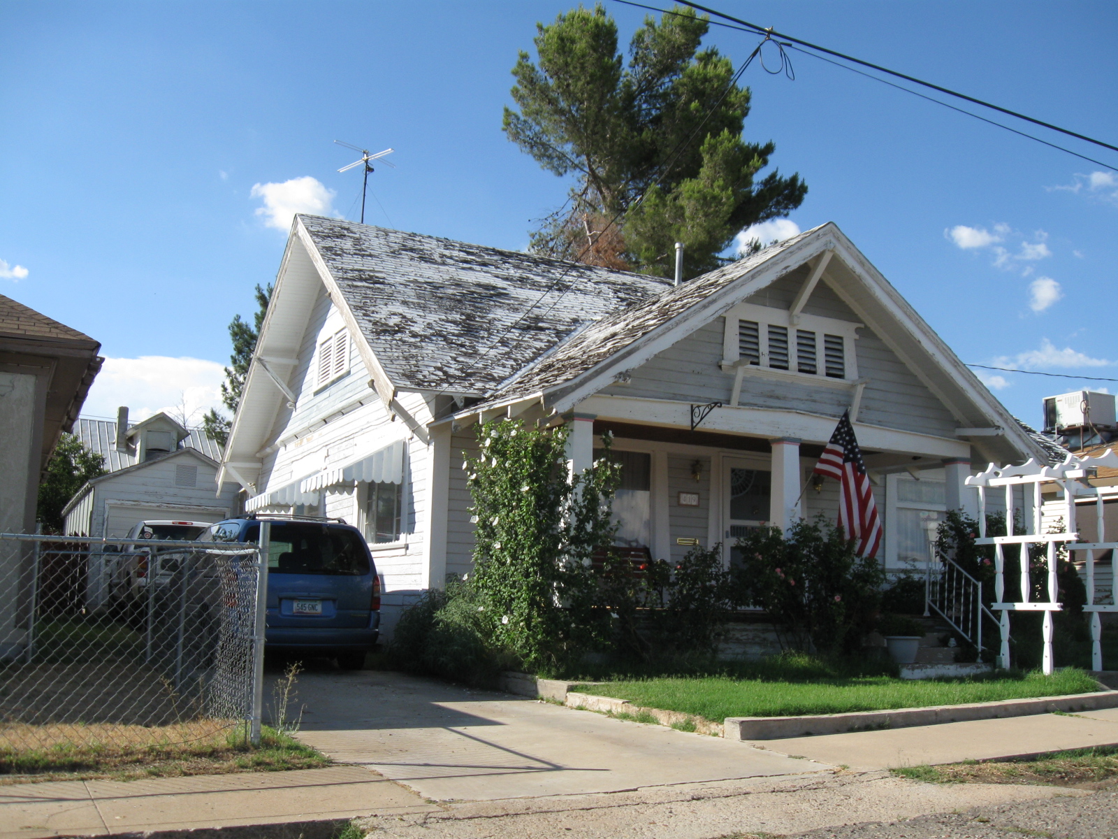 a small white home sits on a quiet sidewalk