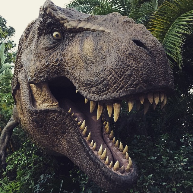 large dinosaur sculpture in the jungle with teeth open