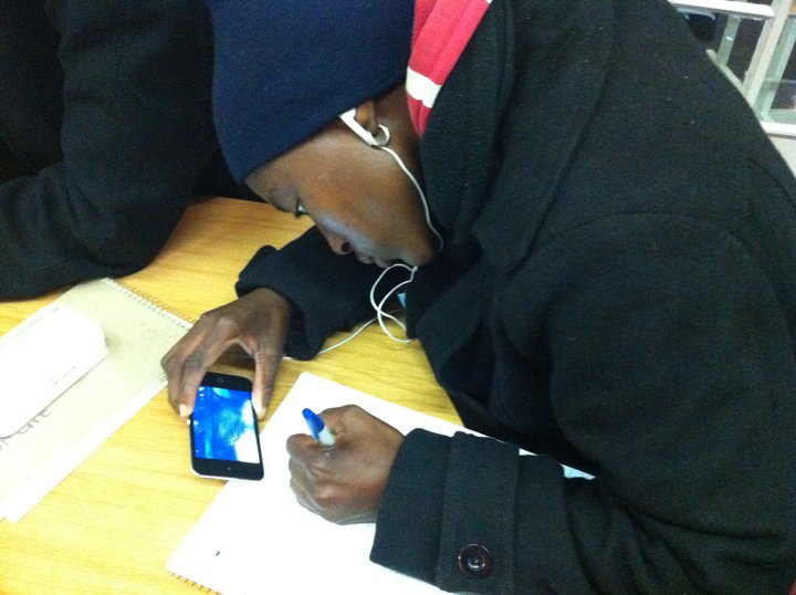 a black female at a table using her cell phone