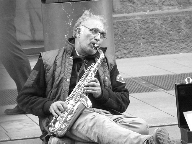 a man is playing his saxophone on the street
