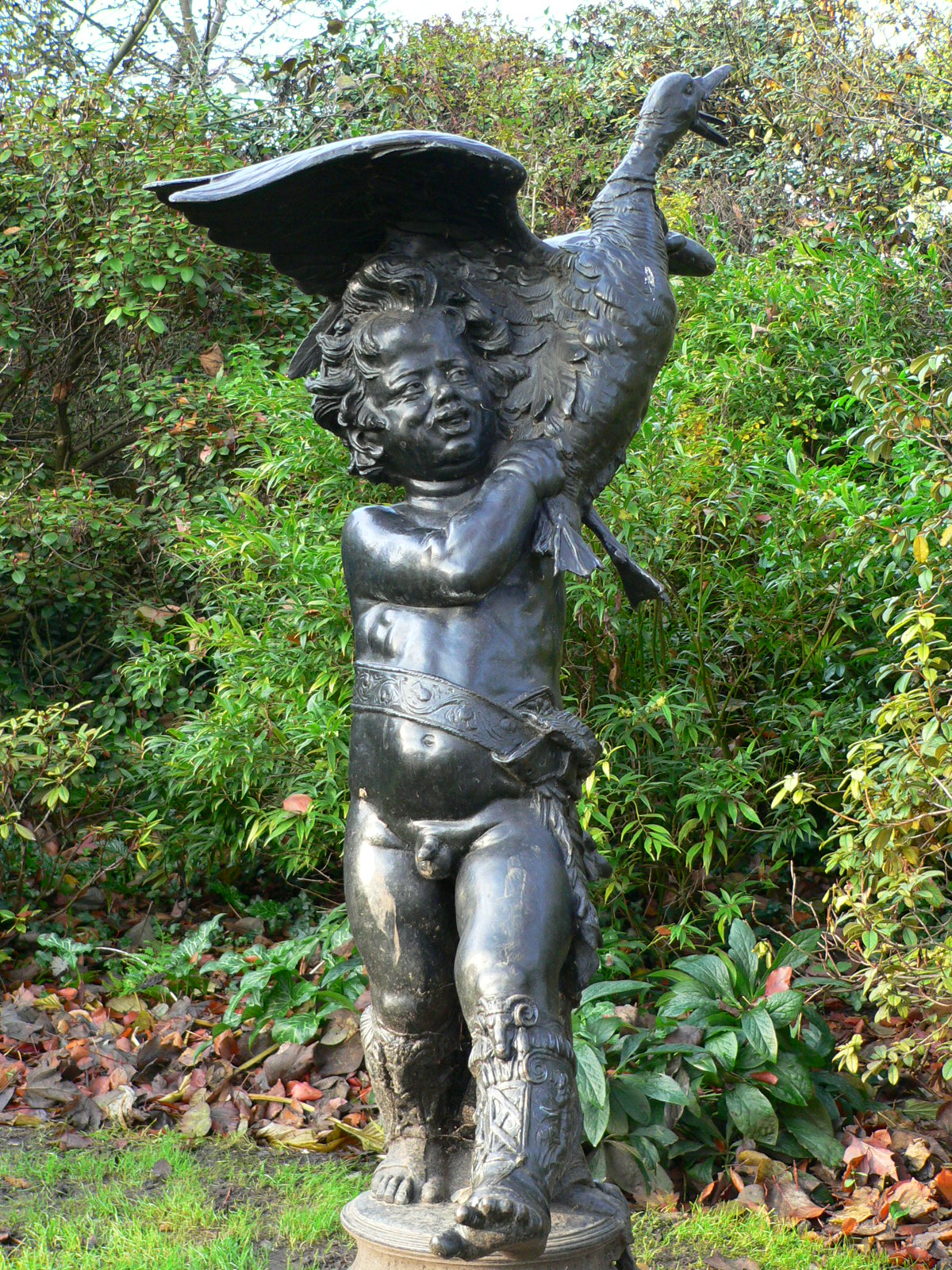 a statue in the garden with leaves surrounding it
