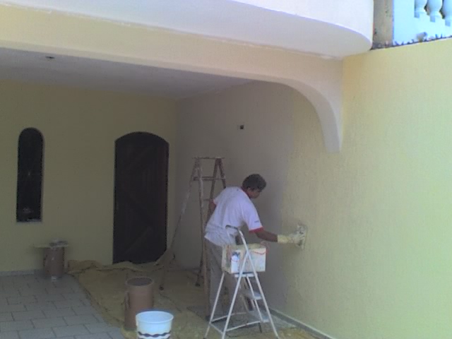 a man paints a room yellow on the outside