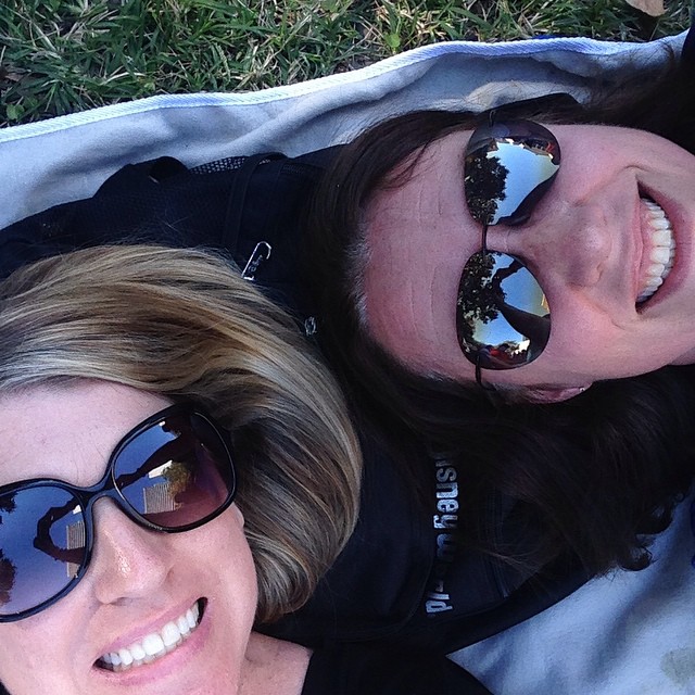 two women laying on the ground smiling and posing for a po