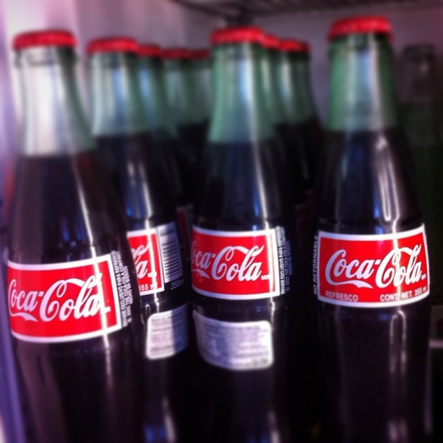 bottles of coca cola sitting on a shelf