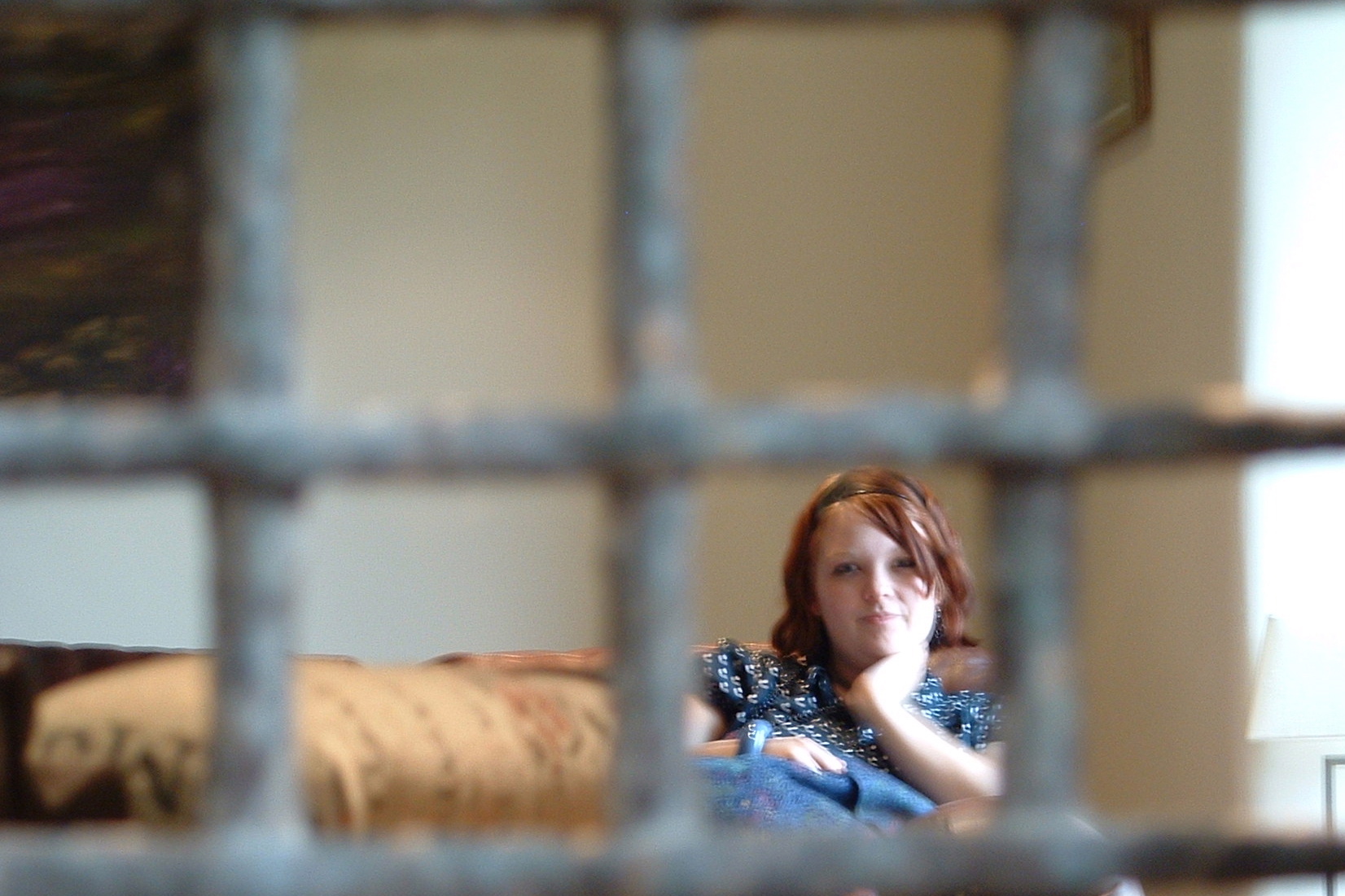 the young woman is looking out through the  bars