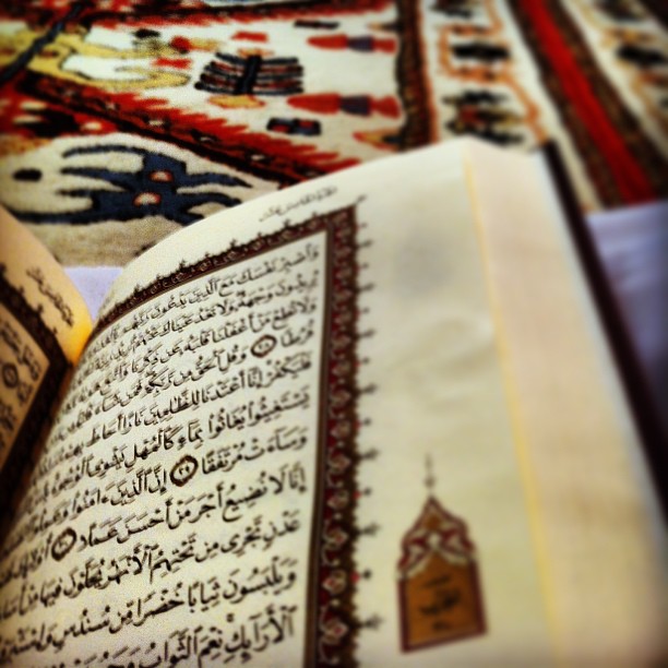 an open book with islamic writing on top