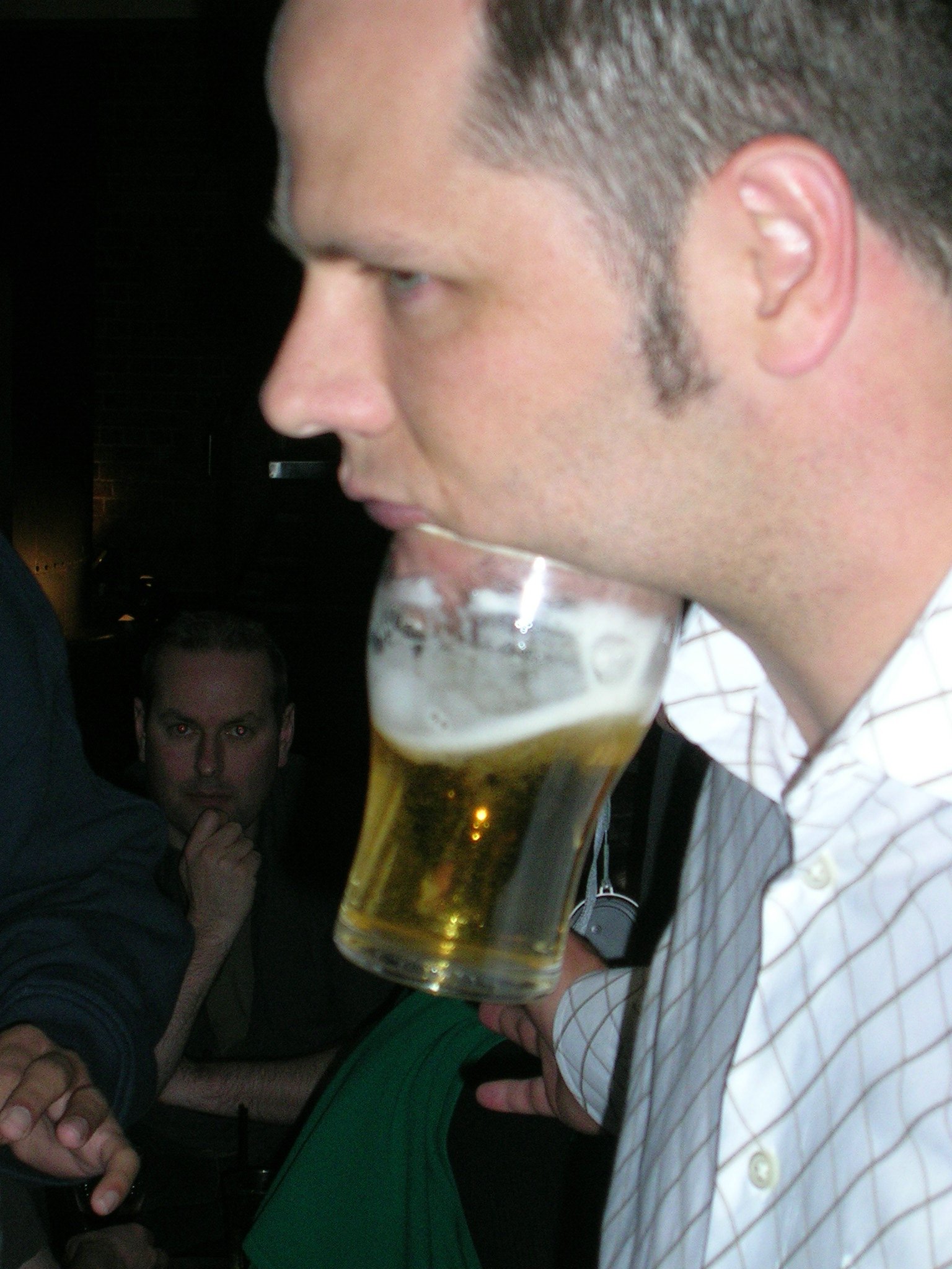 a man wearing a striped shirt has a beer mug with soing in it