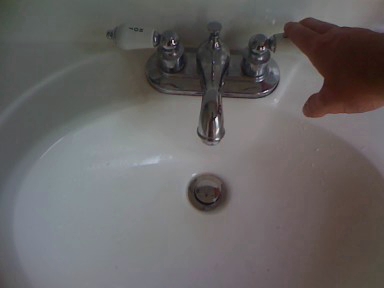 a person is pointing towards a white sink