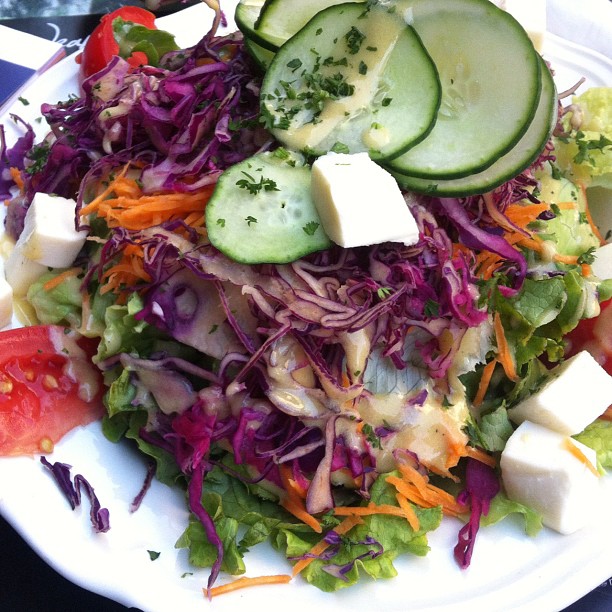 a white plate with salad and cucumbers