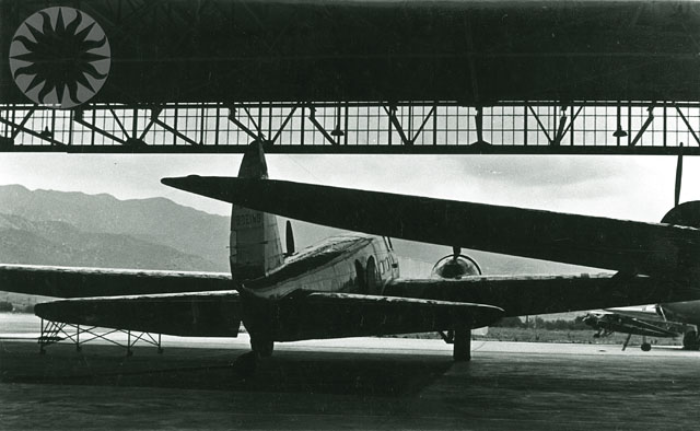 a large propeller airplane parked under a bridge