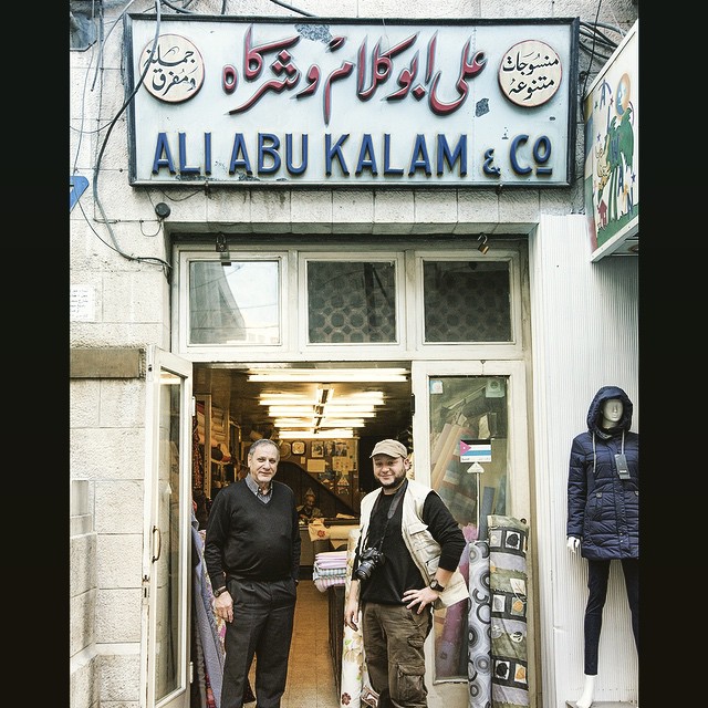 two men are standing outside the entrance of a clothing store