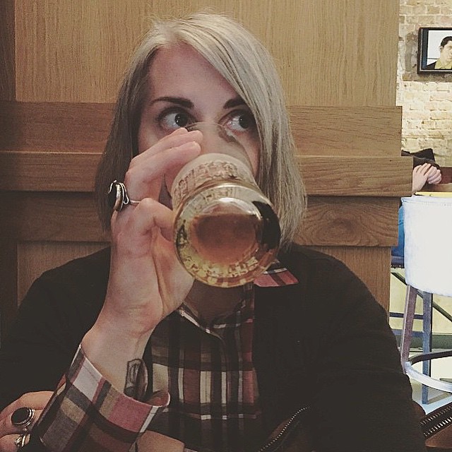 a blonde woman in plaid shirt drinking from a cup