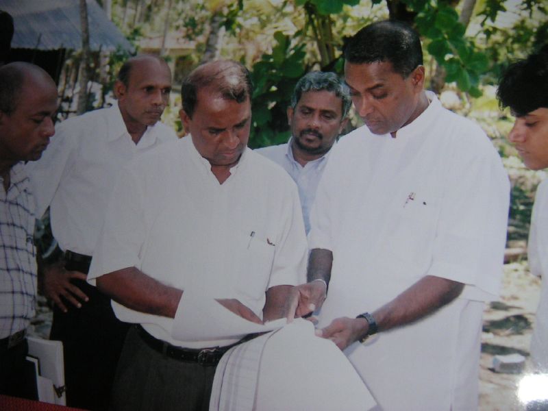 five men standing close together looking at paper