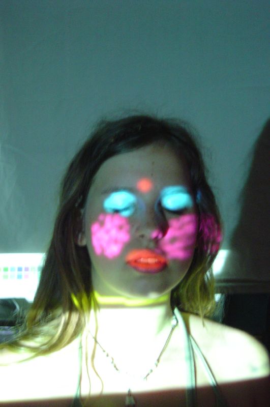 a girl with glowing blue and pink eyes is shown in the reflection of her face