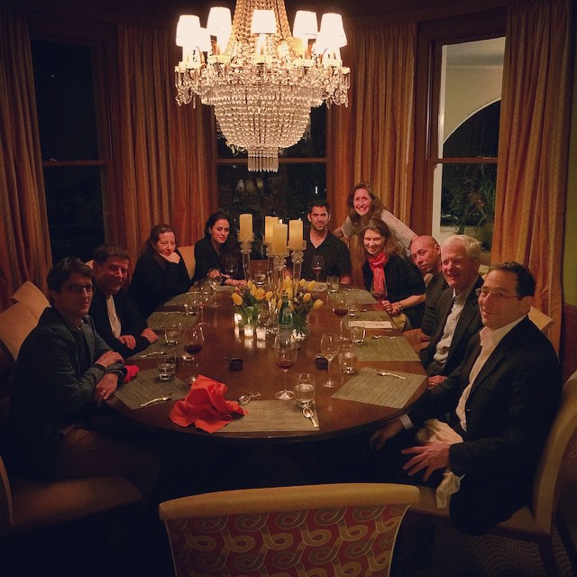 several people gathered around a dining table in a dimly lit room