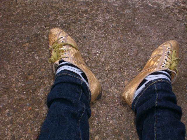 a person with gold shoes on walking on some dirt
