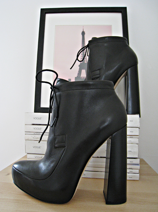 a pair of black leather heels sitting on top of a table