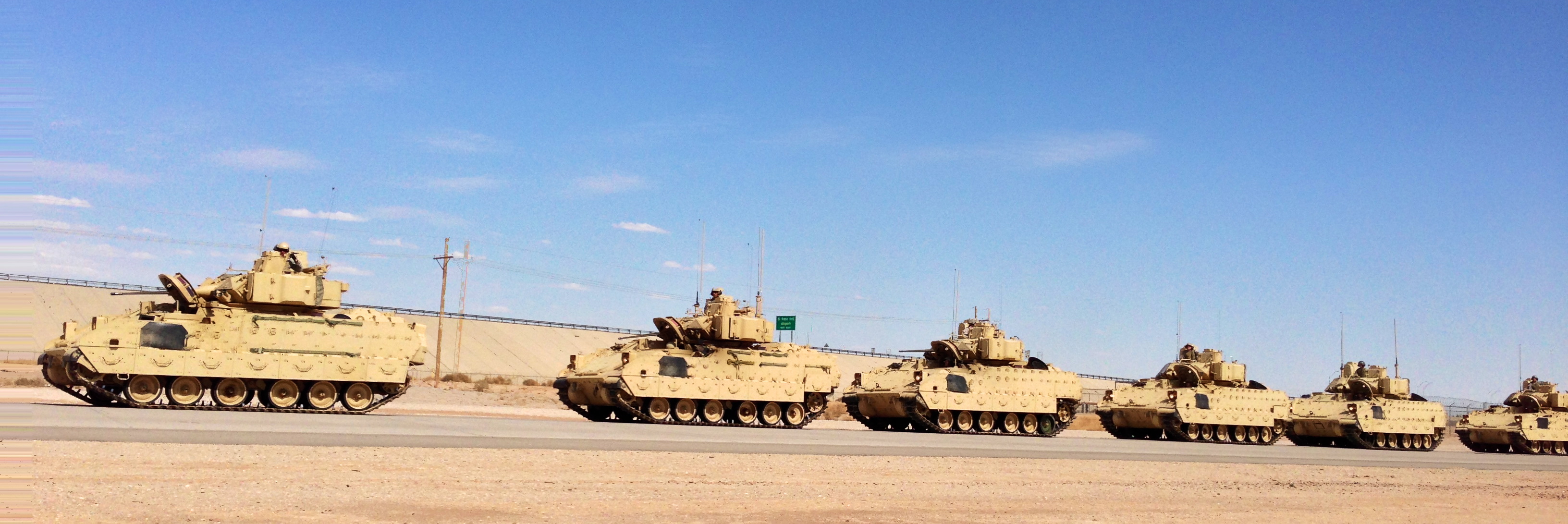a large fleet of tanks traveling down a road