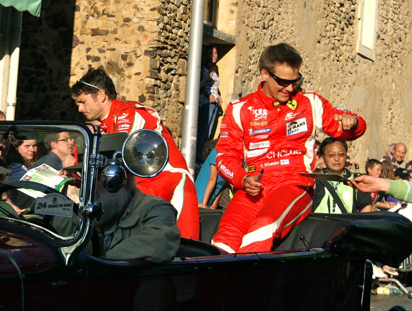 the two men in red are talking on the back of a car