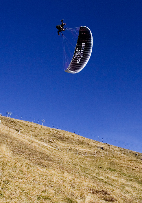 a man kiteboarding over the top of a hill