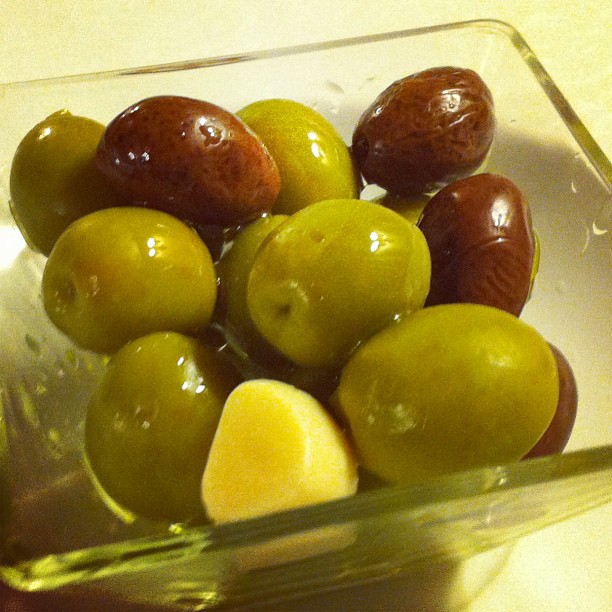 olives are sitting in a glass bowl on the table