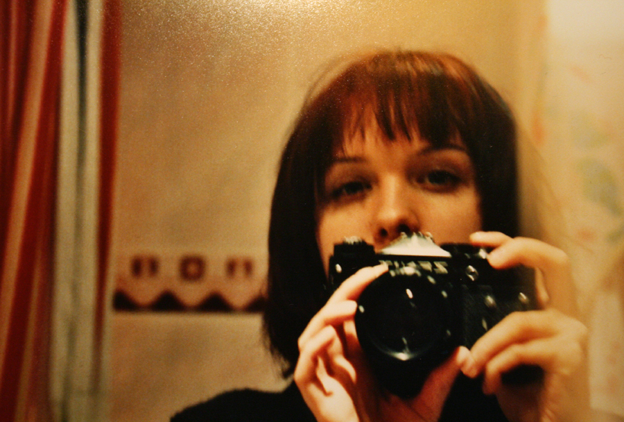 a woman in the reflection of a camera taking a picture