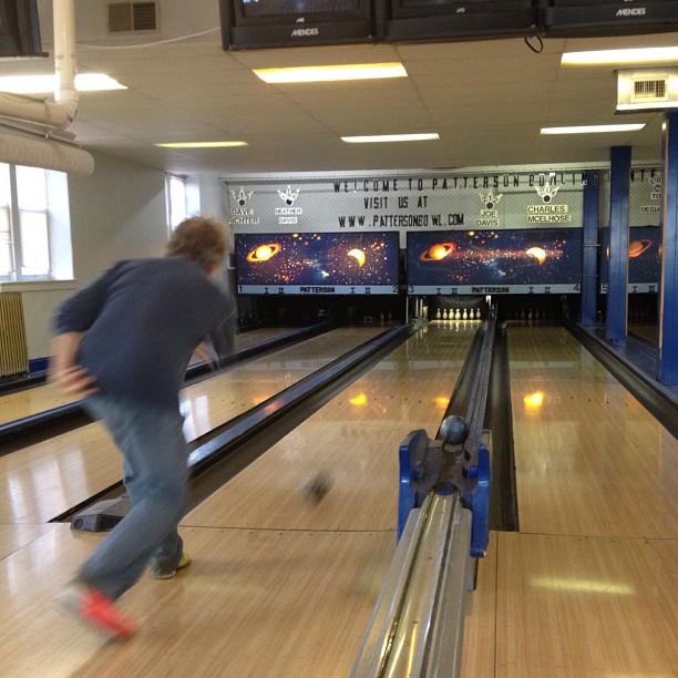 a man riding a bowling ball down a bowling pin